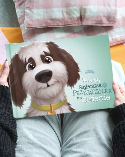 OSOBA TRZYMA KSIĄŻKĘ „KIVA, NAJLEPSZA PRZYJACIÓŁKA NA ŚWIECIE” Z ILUSTRACJĄ PSA NA OKŁADCE.